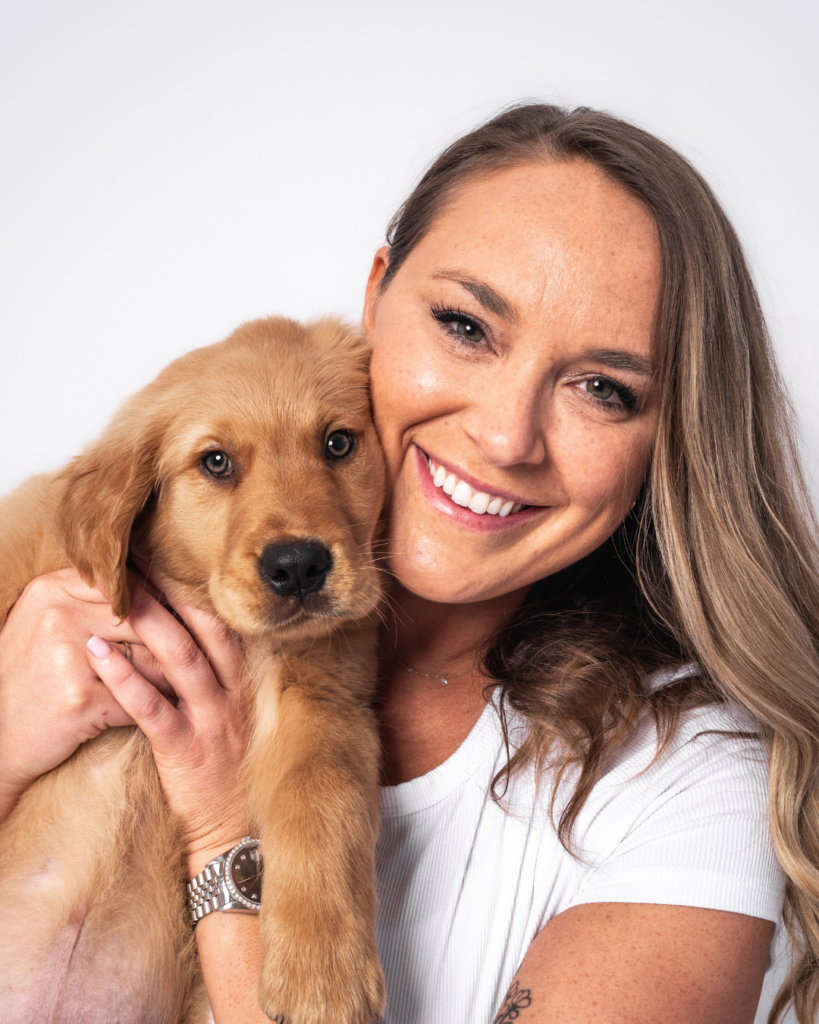 Dog mom holding golden retriever puppy smiling at camera during a San Diego puppy portrait session