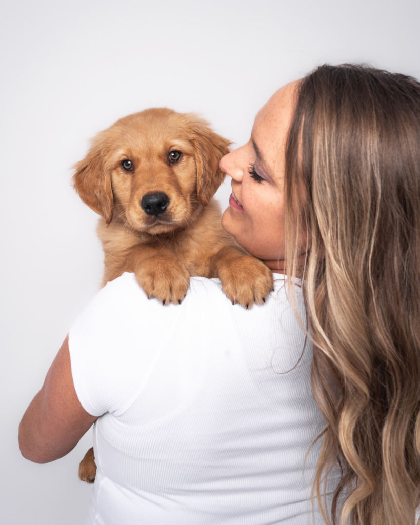 Golden retriever puppy resting over owner’s shoulder during a dog and owner puppy portrait session