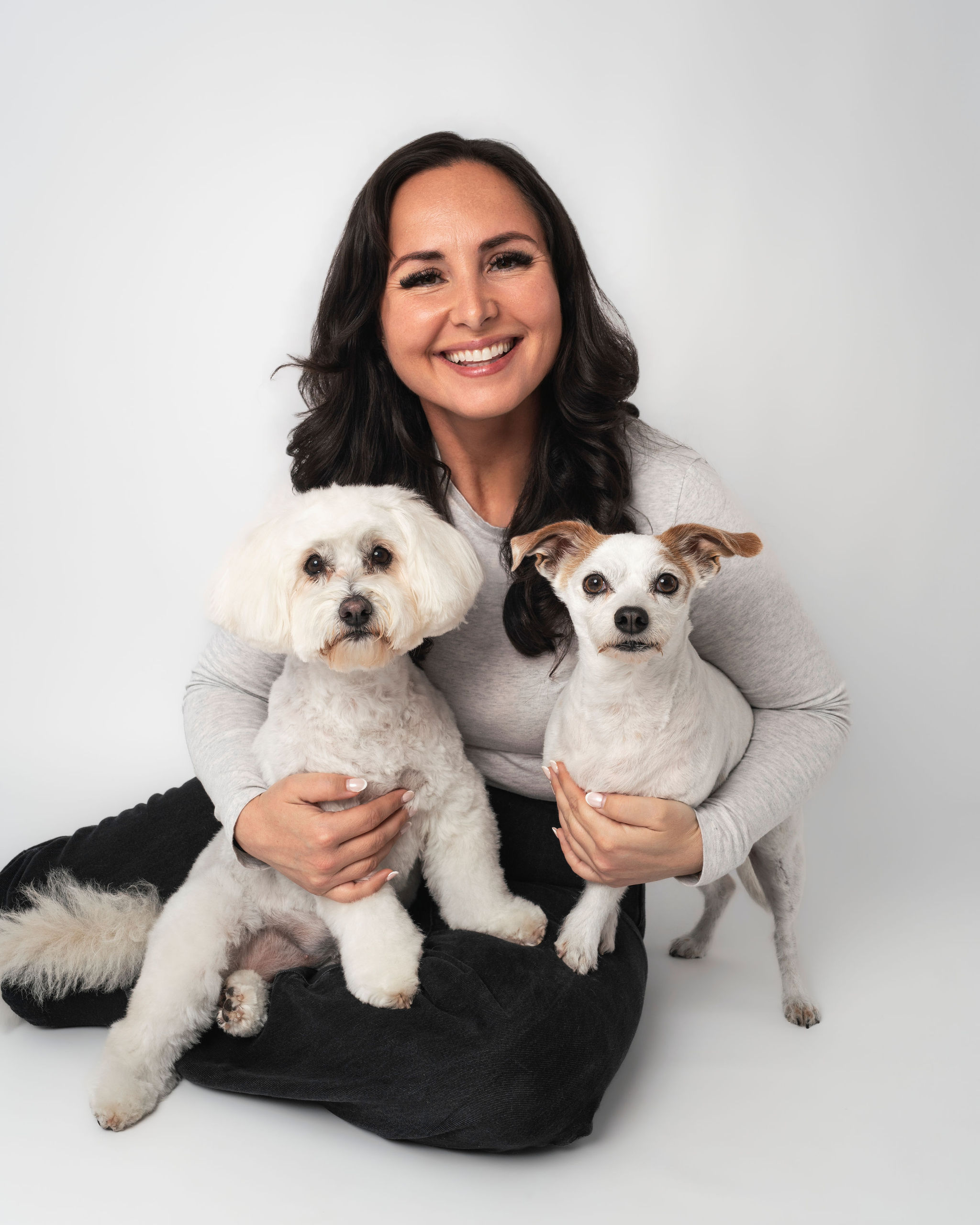 Dog mom posing with two small dogs during family photos with dogs San Diego session