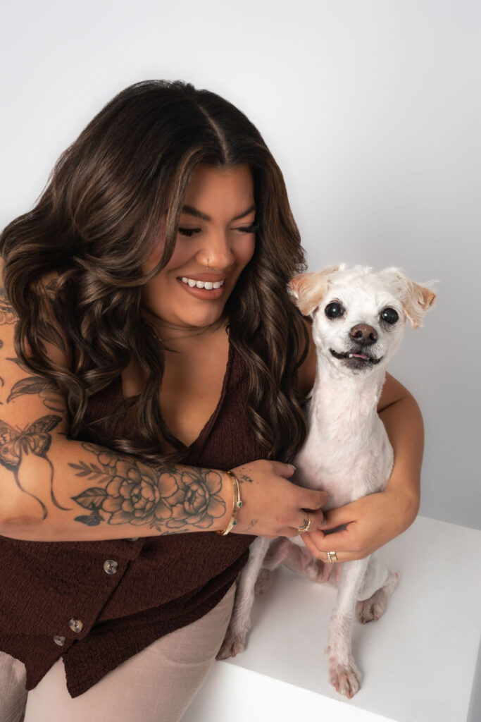 Dog mom holding a small white dog during a San Diego studio dog photography session, capturing a joyful and affectionate portrait together