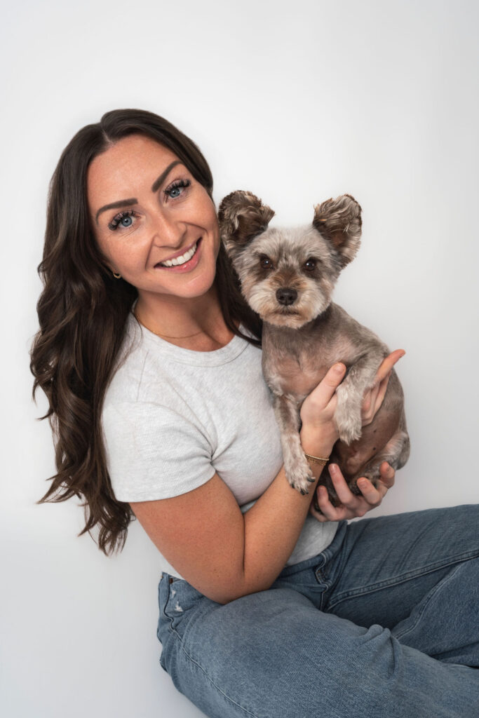 Woman holding yorkie mix dog during family photos with dogs San Diego studio